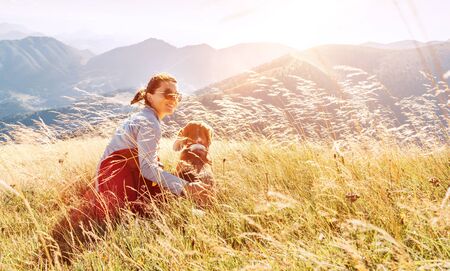 Smiling female hugs her beagle dog resting as they walking in mountains togetherの写真素材
