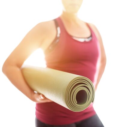 Young Woman holding rolled rubber gymnastic yoga mat on the white background light starting morning yoga exercises. Healthy and active people lifestyle concept.の写真素材