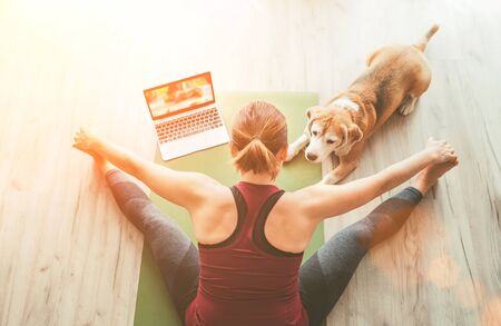 Fit sporty healthy woman sit on mat doing breathing exercises with her beagle dogの写真素材