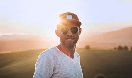 Middle-aged man dressed light white sweater and jeans shorts walking with his beagle dog during sunset evening time. They playing on the just mowing grass meadow. Pets as family members concept image,の写真素材