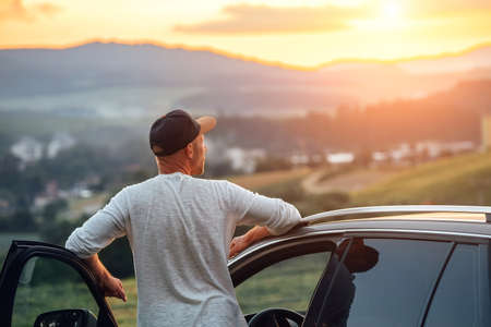 Middle-aged man dressed light white sweater and jeans shorts walking with his beagle dog during sunset evening time. They playing on the just mowing grass meadow. Pets as family members concept image,の写真素材