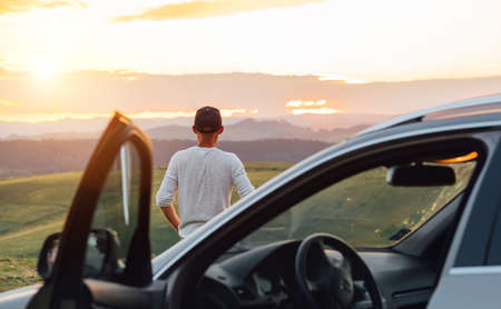 Middle-aged man dressed light white sweater and jeans shorts walking with his beagle dog during sunset evening time. They playing on the just mowing grass meadow. Pets as family members concept image,の写真素材
