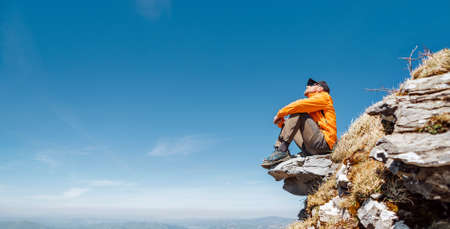 Active people and European tourism concept image. Dressed bright orange jacket hiker in baseball cap...