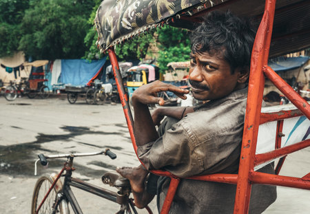 New Delhi, India - August 14, 2016: Poor Rickshaw man worker waiting for clients on the city street...