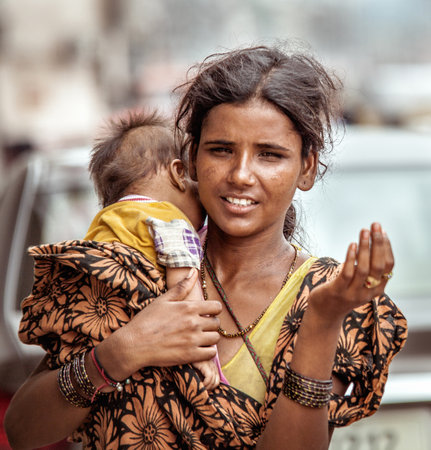 New Delhi, India - August 14, 2016: Young indian beggar woman with baby begs the alms in New Delhi,...