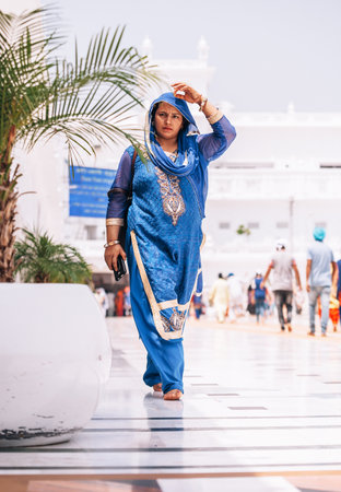 Amritsar, India - AUGUST 15: Portrait of indian woman dressed in female traditional sari (saree) garment walking by the Golden Temple (Harmandir Sahib) on August 15, 2016 in Amritsar, Panjab, India.のeditorial素材