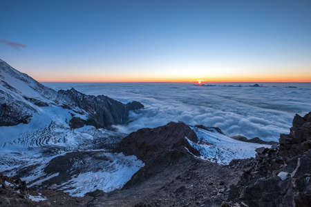 French Alps breathtaking "over the clouds" sunset sky landscape with a Bionnassay Glacier. Mont Blanc ascedding French trekking route "Grand couloir" shot.の写真素材