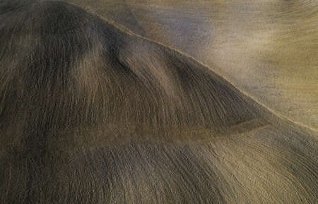 Top aerial view on the cultivated plowed wavy Tuscany field with picturesque evening sunlight spots...