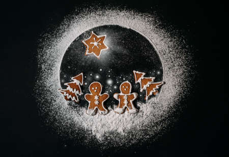 Couple of ginger men walking in Christmas trees cookies forest with Star of Bethlehem above them. Conceptual Earth planet made from sugar powder. Happy New Year and Merry Christmas concept imageの写真素材