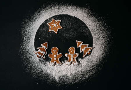Couple of ginger men walking in Christmas trees cookies forest with Star of Bethlehem above them. Conceptual Earth planet made from sugar powder. Happy New Year and Merry Christmas concept imageの写真素材
