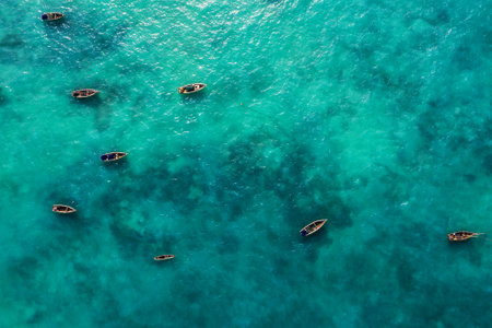 Aerial shot of the fishermen's boats floating on turquoise Indian ocean waves near the Zanzibar island, Tanzania.の写真素材