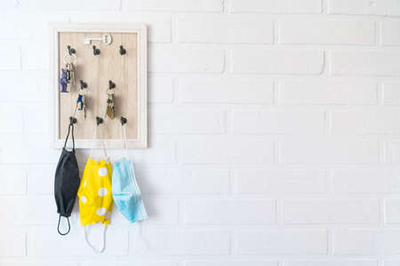 Tree protective face masks on the keys organizer hook on the loft design white background brick wall in the home hallway. Health care concept during COVID-19 pandemic concept background image.の写真素材