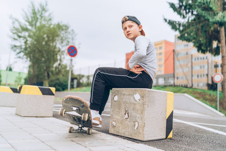 Teenager skateboarder boy portrait in a baseball cap with old skateboard on the city street. Youth generation Free time spending and an active people concept image.の写真素材