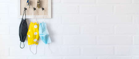Tree protective face masks on the keys organizer hook on the loft design white background brick wall in the home hallway. Health care concept during COVID-19 pandemic concept background image.の写真素材