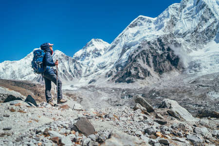Young hiker backpacker female taking brake in hike walking enjoying Khumbu Glacier. High altitude Everest Base Camp route near Gorakshep,Nepal. Nuptse 7861m on background. Active vacations conceptの写真素材