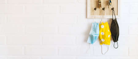 Tree protective face masks on the keys organizer hook on the loft design white background brick wall in the home hallway. Health care concept during COVID-19 pandemic concept background image.の写真素材