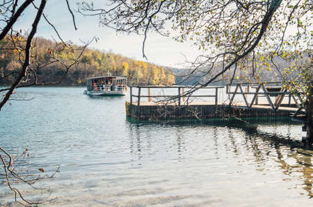 Croatia nature park Plitvice Lakes in autumn soft colors. A ferry full of people departed from the wooden pier on the lake.の写真素材