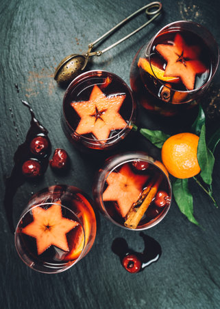 Table still-life top view with hot Mulled wine and spices, fruits, cinnamon served in thin glass mugs on the stone tray. Christmas and New Year celebration concept image.の写真素材