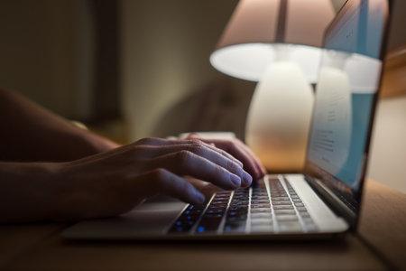 Writer typing modern computer keyboard writing novel in the evening house muffled light. Distance or freelance work or home office on worldwide quarantine time concept imageの写真素材