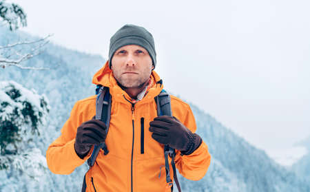 Man dressed bright orange softshell jacket with backpack have trekking on the winter mountains route. Active people or survival in the nature concept image.の写真素材
