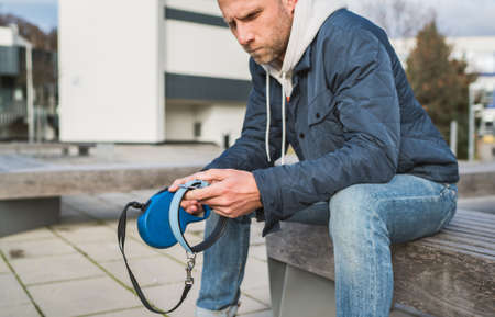Broken with grief man dog owner is grieving sitting on a bench with the lovely pet collar and deep weeping about animal loss. Home pets relatives and love concept.の写真素材