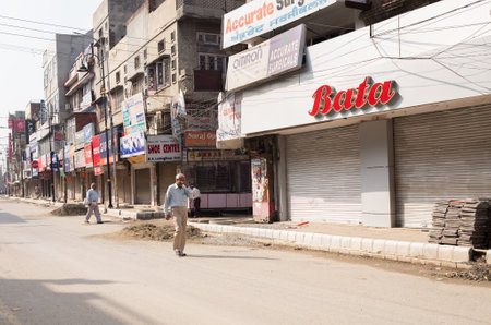 Amritsar, India - AUGUST 15: Bata Corporation multinational footwear and fashion accessory retail store. Man walking by dusty Indian street on August 15, 2016 in Amritsar, Panjab, India.のeditorial素材