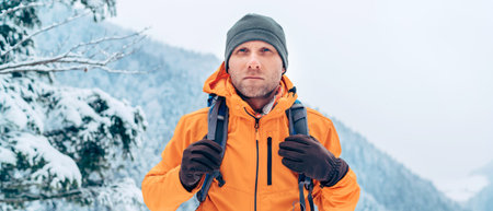 Man dressed bright orange softshell jacket with backpack have trekking on the winter mountains route. Active people or survival in the nature concept image.の写真素材