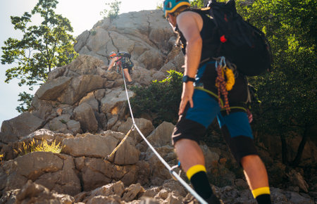 Climbers woman and man in protective helmets and climbing harnesses ascending cliffs on rock wall in Paklenica National park site in Croatia. Active extreme sports time spending concept.の写真素材
