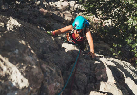 Active Woman in protective helmet and sunglasses on cliff rock wall lead climbing using rope and climbing harness in Paklenica National park, Croatia. Active extreme sports time spending concept photoの写真素材