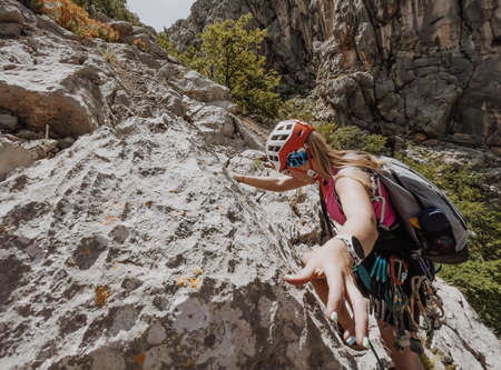 Athletic Woman in protective helmet and harness with rope and quickdraws climbing on cliff rock wall using in Paklenica National park site in Croatia. Active extreme sports time spending concept.の写真素材