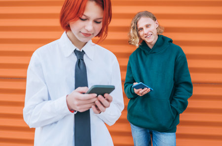 Smiling caucasian teens friends boy and a girl portraits browsing their smartphone devices. Careless young teenhood time and a modern technology concept image.の写真素材