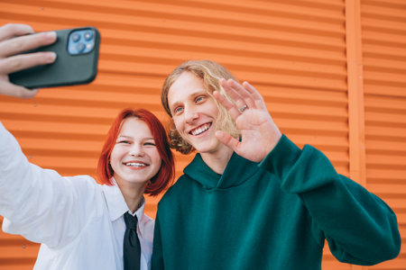 Portraits of two smiling caucasian teen friends boy and girl posing for selfie using a smartphone. Careless young teenhood 
 time and modern technology concept image.の写真素材