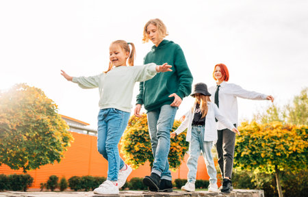 Smiling teenager boy and a laughing sisters girls kids walking in row in the autumnal sunny city park.Careless young teenhood time and a outdoor time spending concept image.の写真素材