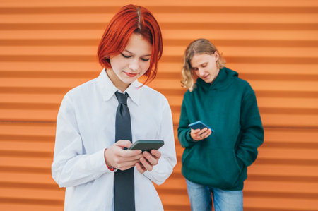 Smiling caucasian teens friends boy and a school girl portraits browsing their smartphone devices. Careless young teenhood time and a modern technology concept image.の写真素材