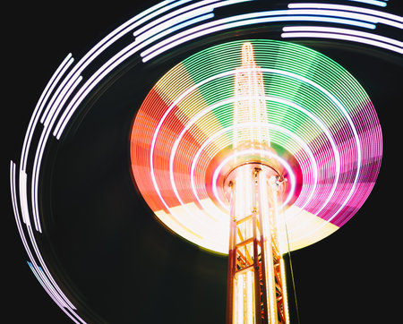 Multicolored Star Flyer tall Carousel rotating on long chains in an amusement park. Entertainment and leisure activities concept.の写真素材