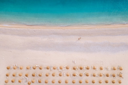 Sun umbrellas rows and sunbeds Myrtos Beach unique turquoise water seashore with a bright white pebbles often proclaimed as one of best beaches in Greece. Kefalonia island aerial background photo.の写真素材