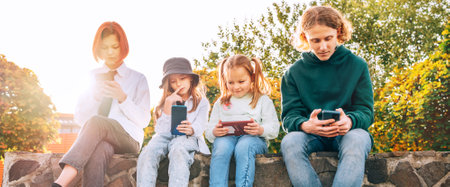 Teenager boy and a sister girls kids sitting and browsing their smartphone devices. Careless young teenhood time and a modern technology concept image.の写真素材