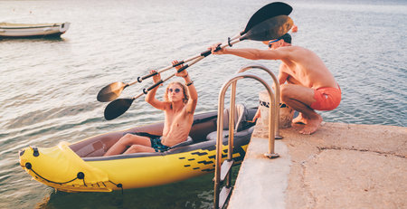 Father with teenager son preparing evening ride loading oars in an inflatable kayak. Adriatic sea harbor in Croatia near from Sibenik city. Vacation and family values image.の写真素材
