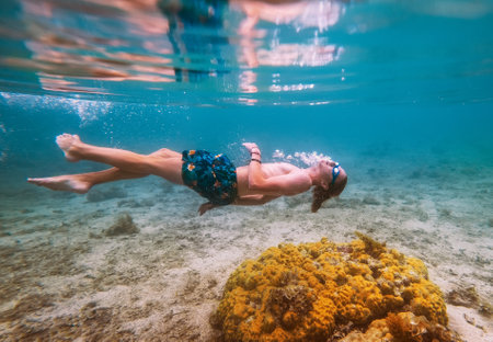 Diving teenage boy snorkeling in underwater glasses making bubbles over the coral reefs underwater photo in the clean turquoise lagoon on Le Morne beach on Mauritius island. Exotic traveling concept.の写真素材