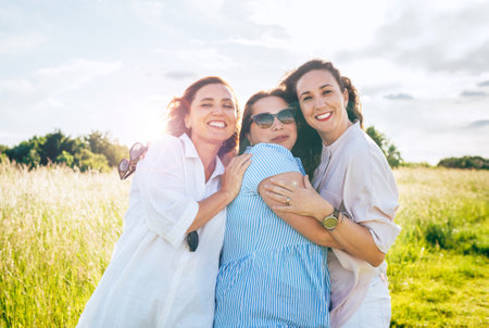 Portrait of three cheerful smiling women embracing during outdoor walking. They looking at the camera. Woman friendship, relations, and happiness concept image.の写真素材