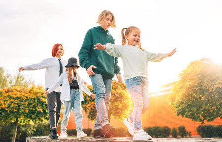 Smiling teenager boy and a laughing sisters girls kids walking in row in the autumnal sunny city park.Careless young teenhood time and a outdoor time spending concept image.の写真素材