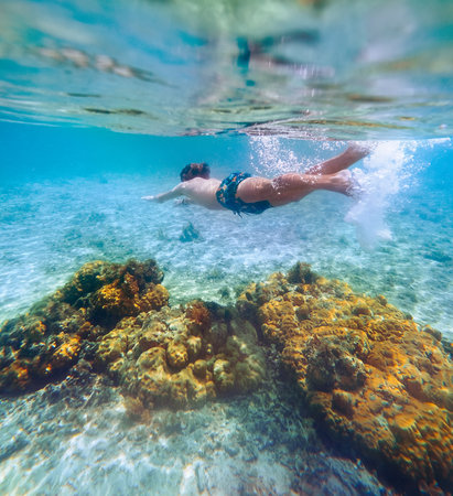 Diving teenage boy snorkeling over the coral reefs underwater photo in the clean turquoise lagoon on Le Morne beach. Mauritius island. Exotic traveling and underwater eco concept.の写真素材
