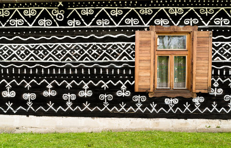 Wooden window on the White and black pattern ornament painting on the dark wood wall in Slovakian old village Cicmany. European history heritage and black and white background concept imageの写真素材