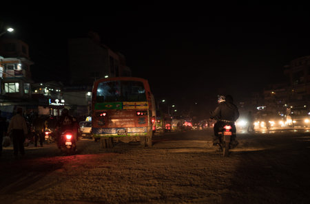 Kathmandu, - Nepal, October 25, 2019: Night traffic buses and moto scooters on the dusty Nepalese streets litted with traffic lights in Kathmandu, Nepal.のeditorial素材