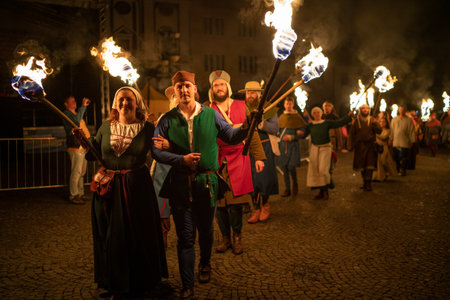 Zilina, Slovak RepubliÑ, Slovakia - July 28, 2023: People dressed in medieval dresses and armored knights with a flaming torches during a fire procession deep night shot in Zilina, Slovakia.のeditorial素材