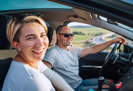Portrait of cheerful smiling young woman with husband have auto journey inside modern car. Safety riding car, car sharing and traveling concept image.の写真素材