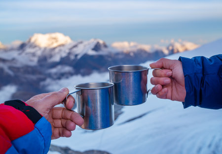 Young woman holding a metal hot tea cup during sunset time from the Mera Peak high camp with snowy seven-thousander mountains. Climbing expedition acclimatization. Active people concept.の写真素材