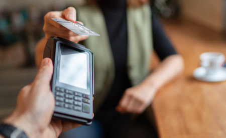 Young woman holding credit doing wireless bank payment with POS terminal process acquire at table in...