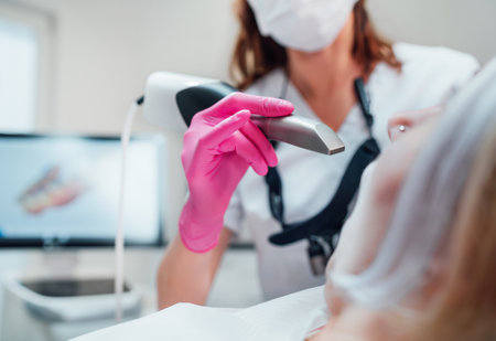 Dentist female doctor in uniform using intraoral 3D dental scanner Machine for clear aligners production. Dental clinic patient visit modern medical ward. Health teeth care, medicare industry concept.の写真素材