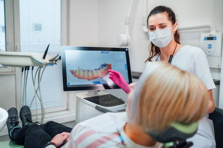 Dentist female doctor in uniform showing scan of intraoral 3D dental scanner Machine to patient. Dental clinic patient visit modern medical ward. Health teeth care, medicare Clear aligners industry.の写真素材